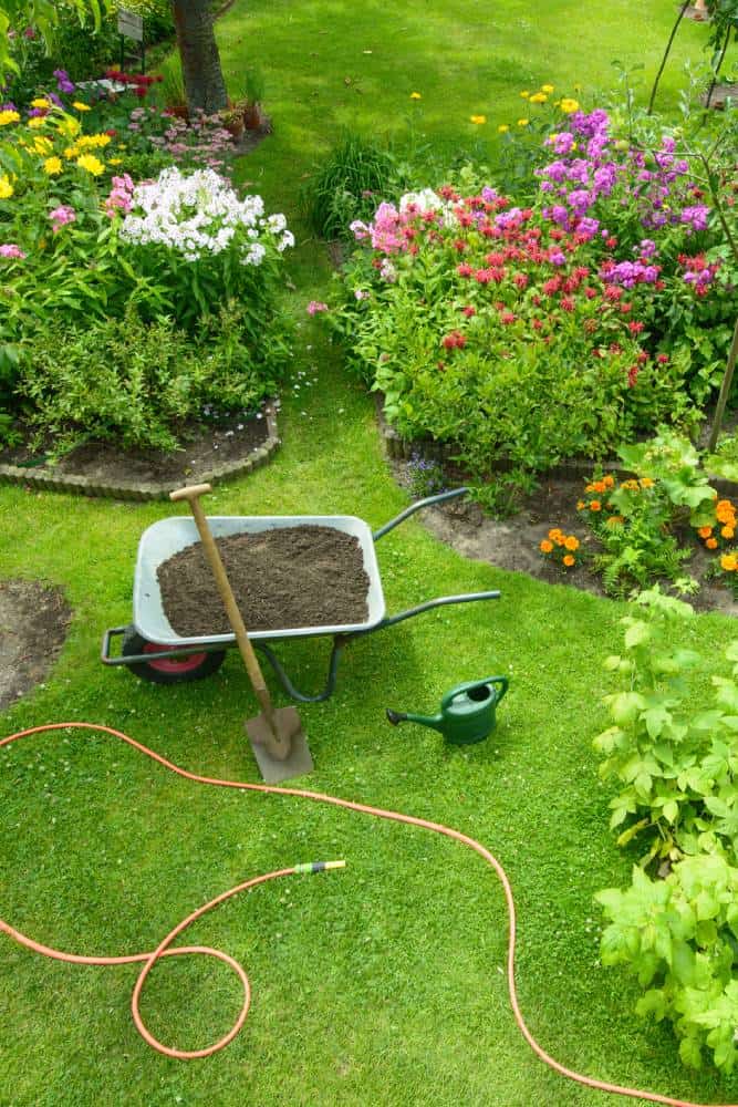 Vibrant garden with wheelbarrow, shovel, and watering can.