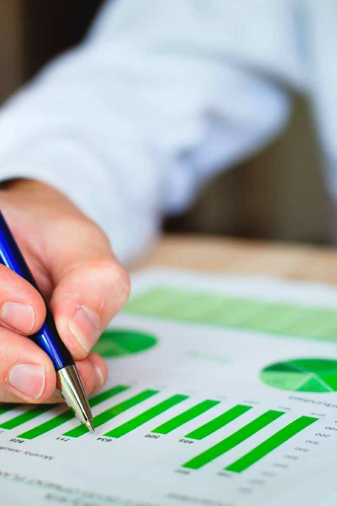 Person analysing financial growth chart with pen.