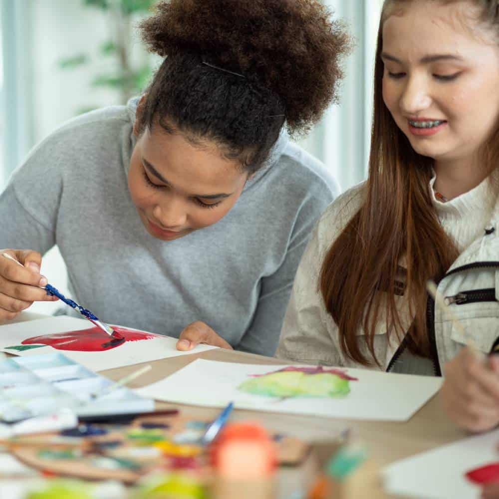 Two teens enjoying a painting session together.