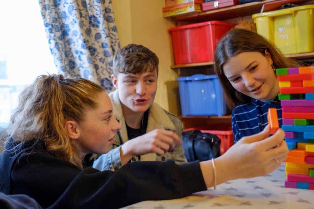 Group of teens playing colorful stacking block game.