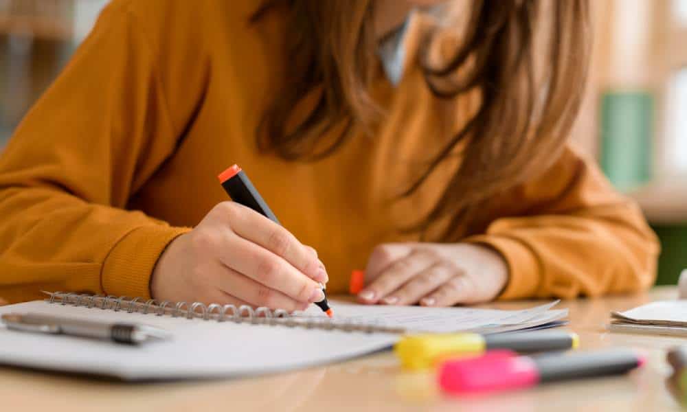 Woman studying with highlighters and notebook.
