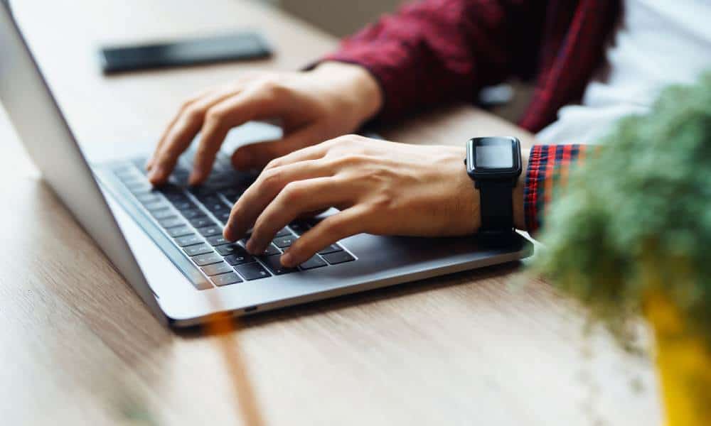 Person typing on laptop with smartwatch