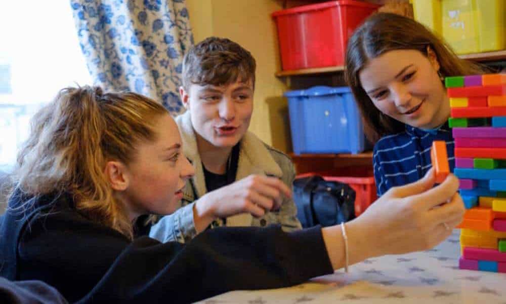 Teens playing Jenga game indoors.
